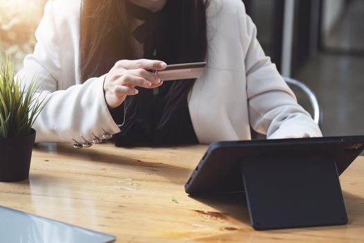 Asian young woman using a tablet and credit card for online shopping.