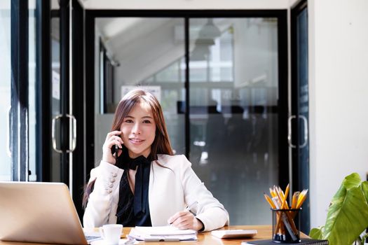 Portrait of a asian businesswoman taking business notes while talking on the phone.