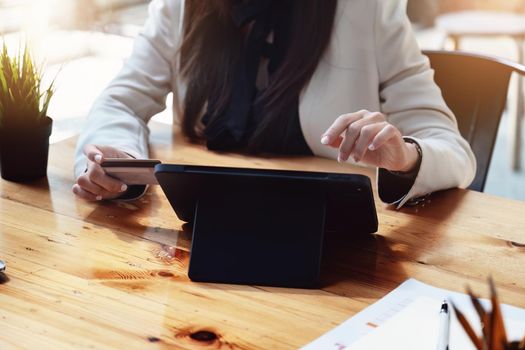 Asian young woman using a tablet and credit card for online shopping.