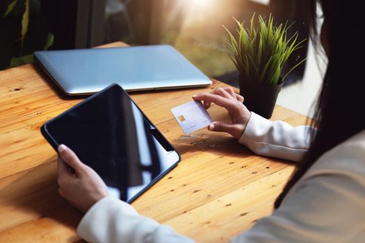 Asian young woman using a tablet and credit card for online shopping.