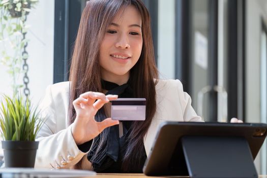 Portrait of Asian young woman using a mobile phone and credit card for online shopping.