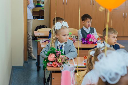 NOVOKUZNETSK, KEMEROVO REGION, RUSSIA - SEP, 1, 2021: First-grade students and teacher are in school classroom at first lesson. The day of knowledge in Russia.