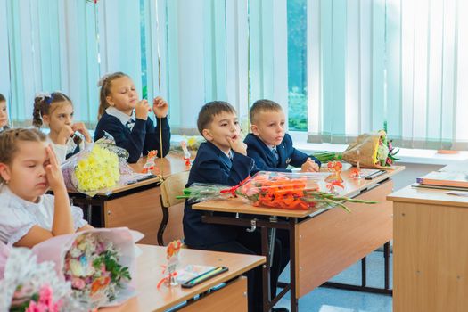 NOVOKUZNETSK, KEMEROVO REGION, RUSSIA - SEP, 1, 2021: First-grade students and teacher are in school classroom at first lesson. The day of knowledge in Russia.