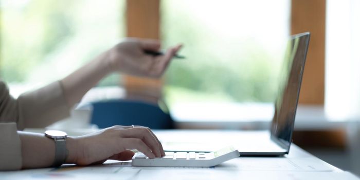 Close up Business woman hand using calculator to calculate the company's financial results and budget. Account Audit Concept..