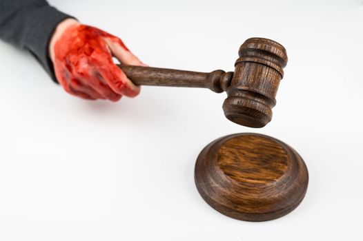 Female judge with bloody hands beats the gavel on a white background