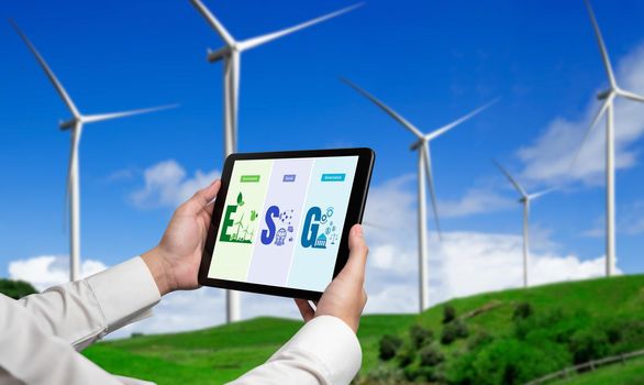 Green business transformation for environment saving and ESG business concept. Businessman using tablet to set corporate goal toward environmental friendly management and alternative clean energy use.