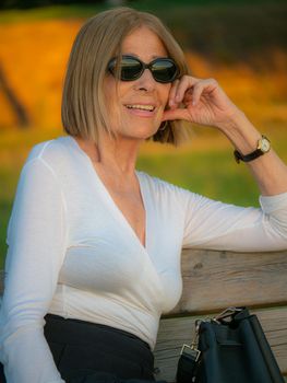 senior fit elegant lady dressed blaka dn white wearing sunglasses enjoying nature in summer