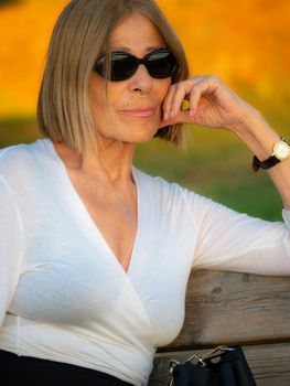 senior fit elegant lady dressed blaka dn white wearing sunglasses enjoying nature in summer