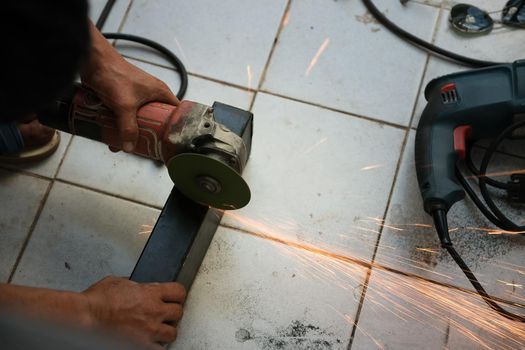 The contractor is using an electric grinder to decorate the steel welding point.