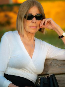 senior fit elegant lady dressed blaka dn white wearing sunglasses enjoying nature in summer