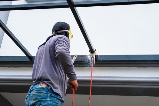 The welder is welding the steel structure to add to the house.