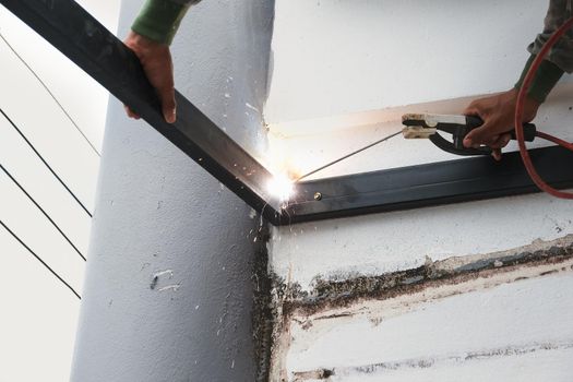 The welder is welding the steel structure to add to the house.