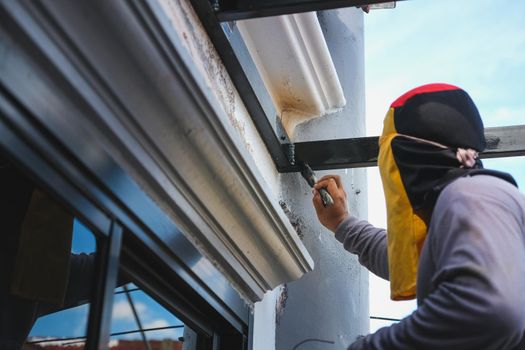 A mechanic is using a paint to paint the steel in matte black.