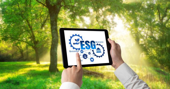 Green business transformation for environment saving and ESG business concept. Businessman using tablet to set corporate goal toward environmental friendly management and alternative clean energy use.