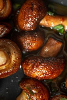 Roasted mushrooms in oil. Forest mushrooms cooked in a pan. Diet for a healthy diet. Fried mushrooms. Golden colored, beautifully roasted mushrooms. Vegetarian Food. Close up. Vertical shoot and top view
