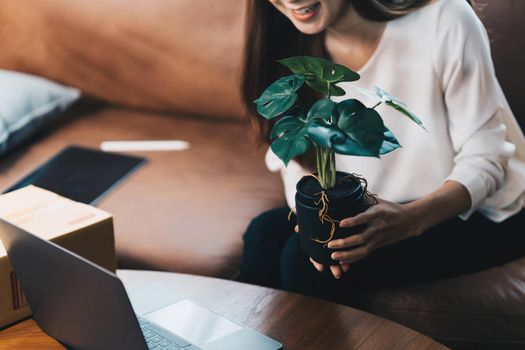 Image of Young asian woman startup freelance with flower and showing to customer by computer laptop. Online marketing packing box delivery concept