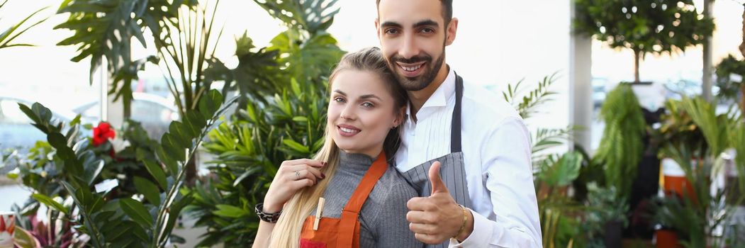 Portrait of young male and female consultants work in flower delivery shop and sale indoor plants. Business, floral design, creative studio, nature concept