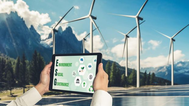 Green business transformation for environment saving and ESG business concept. Businessman using tablet to set corporate goal toward environmental friendly management and alternative clean energy use.