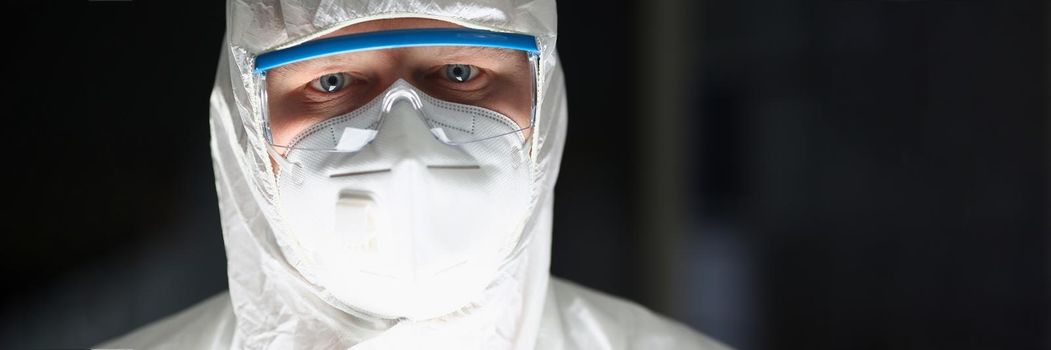 Portrait of male lab worker in protective respirator and white coverall, smart scientist. Male chemist in eyeglasses work on research. Science, lab concept