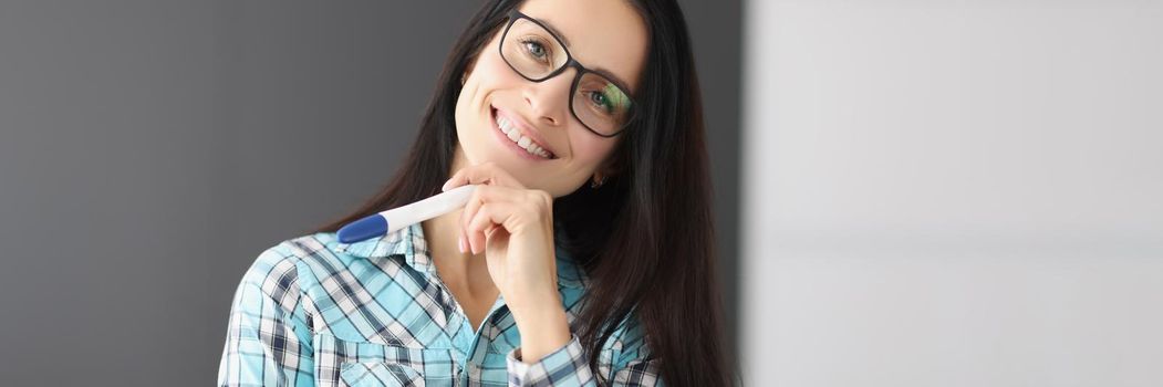 Portrait of young happy female hold pregnancy test, female got big news and smiling. Woman shine with happiness. Pregnancy, new period, life change concept