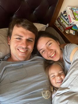 Smiling mom, dad and little daughter lie in bed. High quality photo