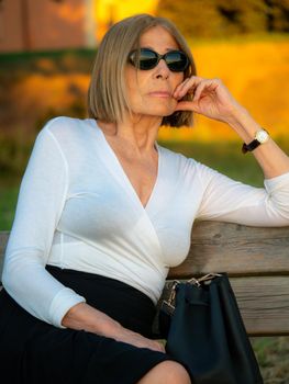 senior fit elegant lady dressed blaka dn white wearing sunglasses enjoying nature in summer