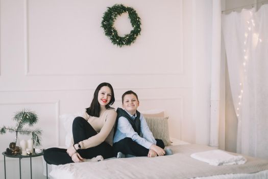 Happy family at home. Son with mom enjoying time together in a cozy room. Motherhood concept.