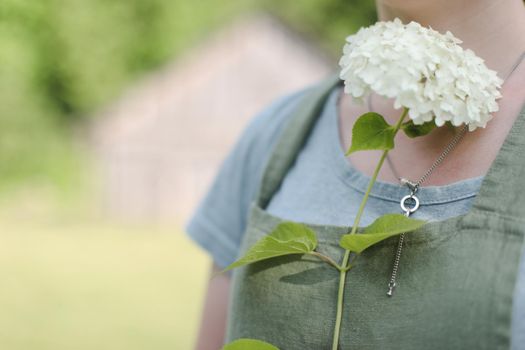 young woman in apron holding flowers in the garden in summer. gardening and profession concept