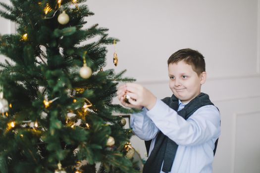 child boy decorating Christmas tree in a home interior and festive atmosphere