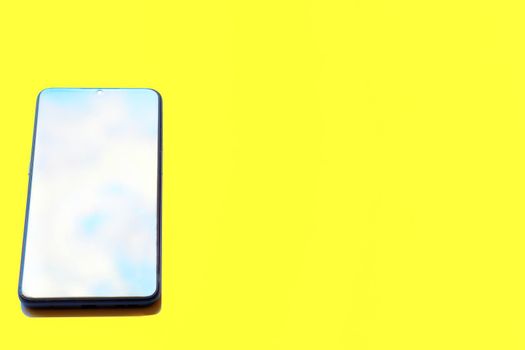 a mobile phone that performs many of the functions as computer, use having a touchscreen interface, internet acces. Mobile phone smartphone with cloudy sky on screen isolated on yellow background