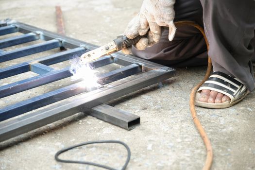 The welder is welding the steel structure to add to the house.