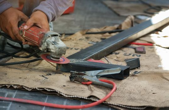 The contractor is using an electric grinder to decorate the steel welding point.