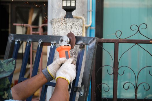 The contractor is using an electric grinder to decorate the steel welding point.