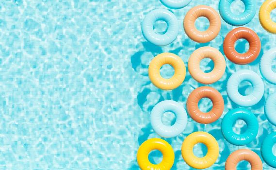 3D rendering top view of colorful inflatable swim rings floating in water of outdoor pool on sunny summer day