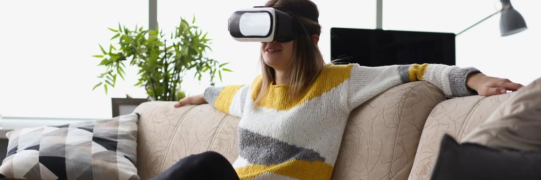 Portrait of female sit on couch wear vr glasses modern device at home and enjoy spare time. Visual effects, fun leisure. Innovation, entertainment concept