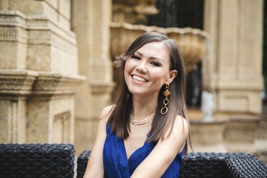 Asian pretty smiling woman in blue dress outdoor portrait.