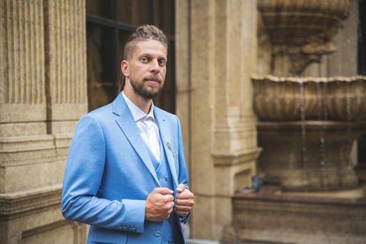 Caucasian man in blue three piece suit look at camera, outdoor portrait.