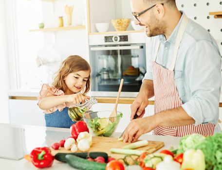 Daughter and father preparing food in the kitchen