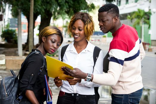 Students standing in the street after class looking at book smiling.