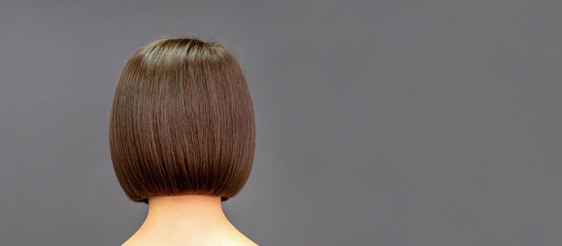 Back view of bob hair of a young woman on dark background