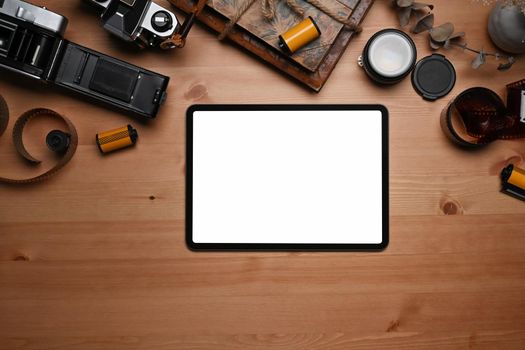 Mock up digital tablet, film rolls, retro camera and book on wooden table.