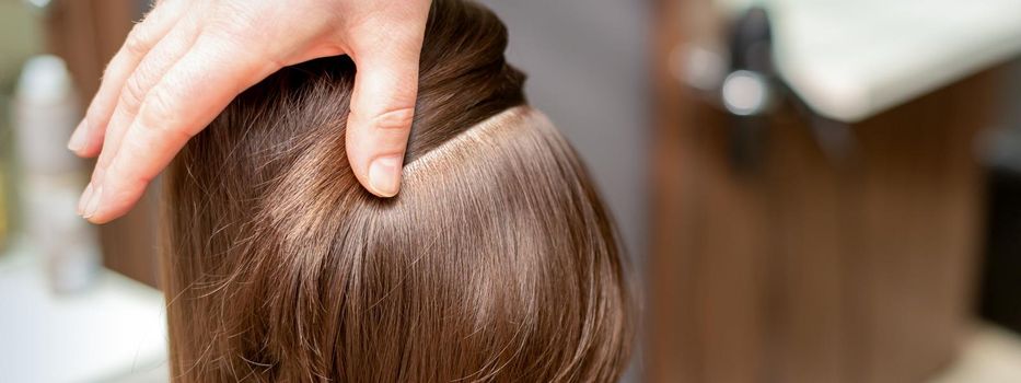 Hairdresser checks short brown hairstyle of a young woman in a beauty salon