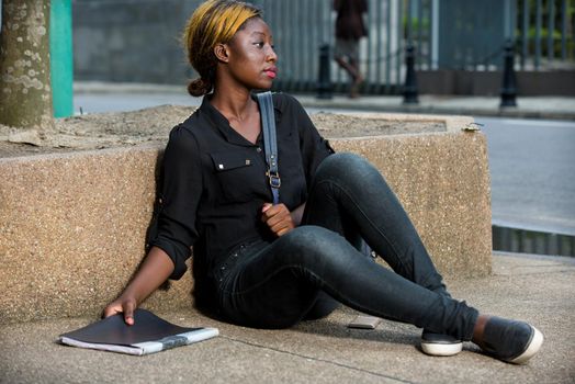 Young girl doing her chores and homework sitting on campus outside. College student holding his book