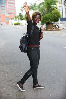 Young student standing in the street after class greeting with a smile.