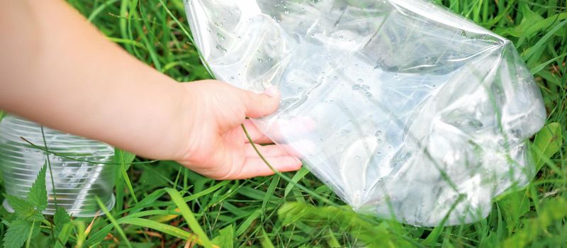 Used empty plastic bag in hands of a little girl while cleaning the park from debris