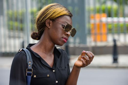 student wearing sunglasses walking and reading mobile phone messages outdoors