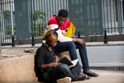 two young students, girl and boy sitting together and reading their lessons outdoors.concept education and returns to school