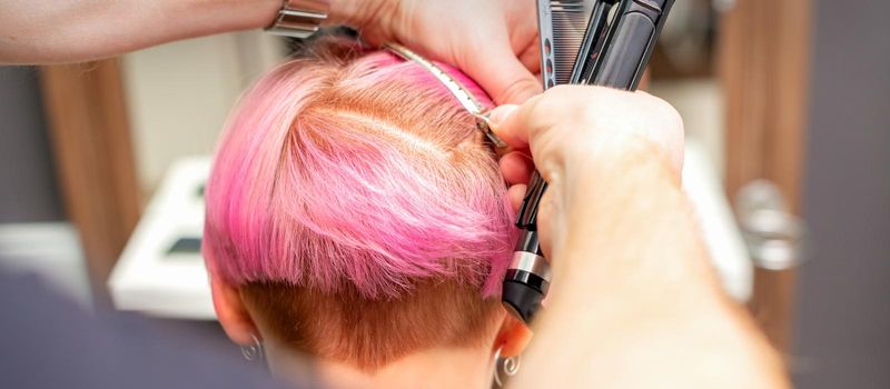 Hairdresser pinches hair with the clip before doing hairstyle in a hair salon