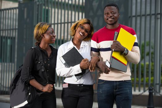 Group of happy teenage students in casual outfit with notebook outside campus