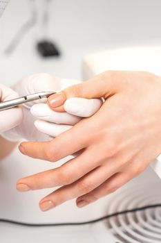 Manicure master is removing cuticles with a nail clipper in a nail salon